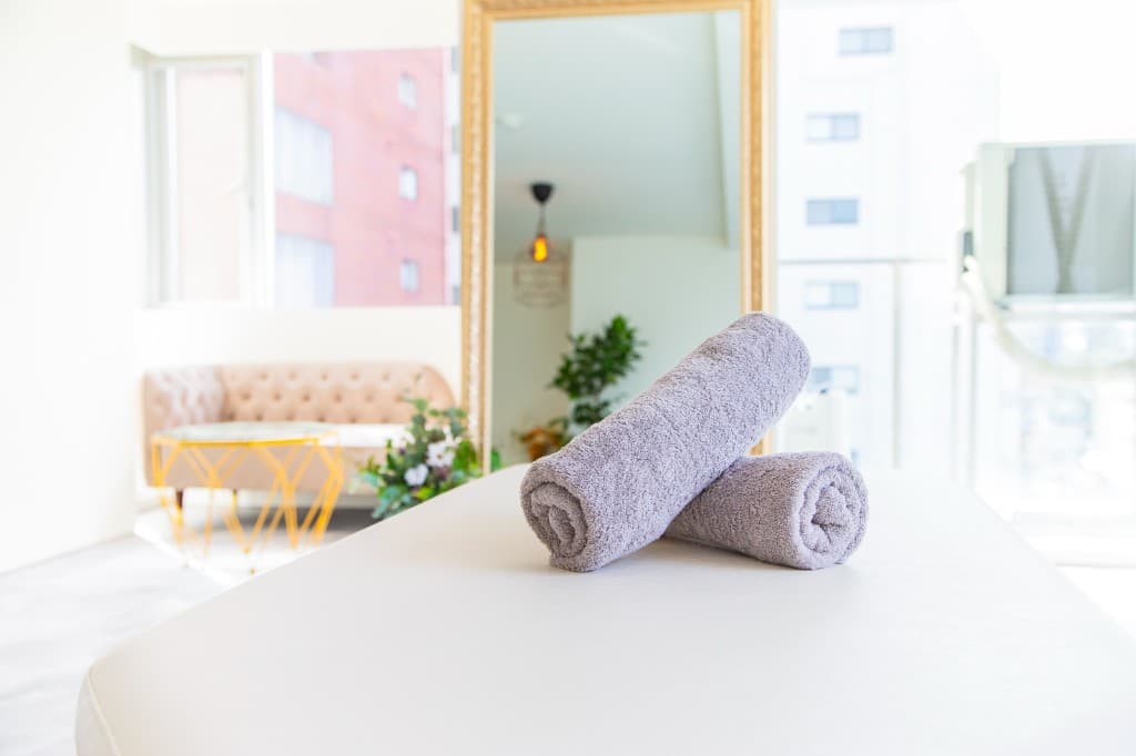 明るい施術室。施術台に置かれたタオルと、自然光が差し込むリラックスできる空間