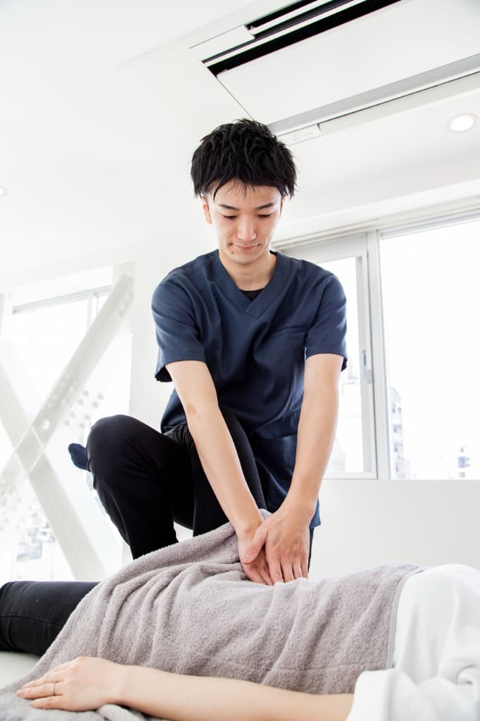 施術台でお客様の腹部にタオルをかけ、腸もみを行っている施術の様子。