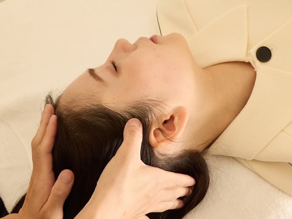 施術台で脚を挙げた姿勢をサポートし、整体で体幹を整えている施術の様子。