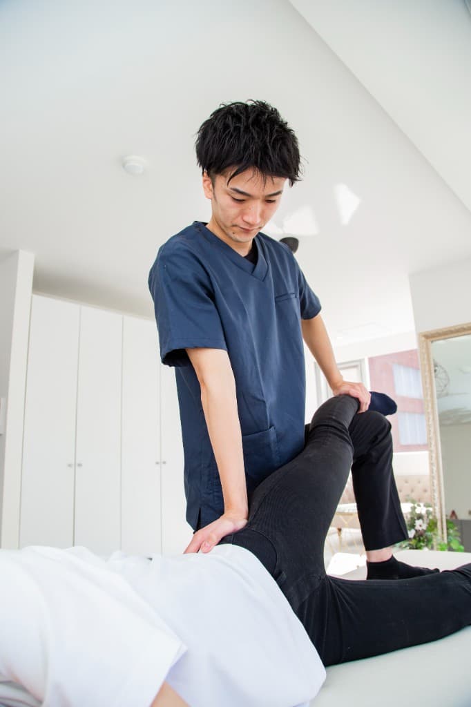 施術台で脚を挙げた姿勢をサポートし、整体で体幹を整えている施術の様子。